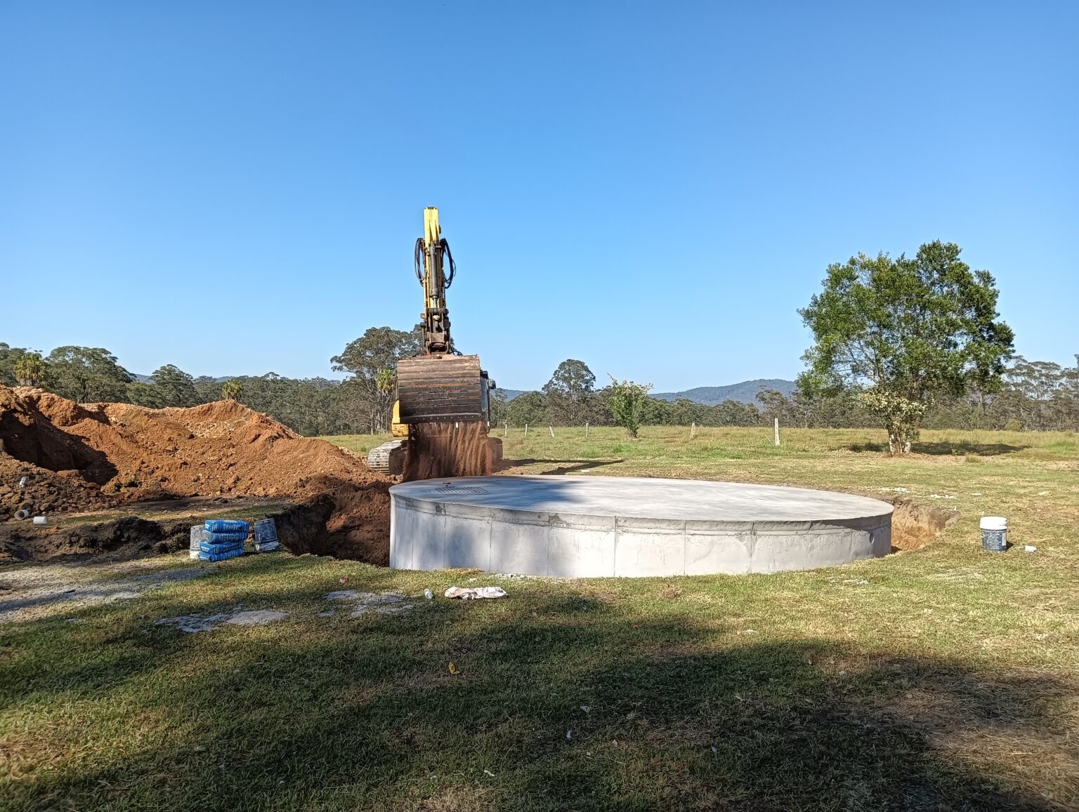 excavator back filling a water tank