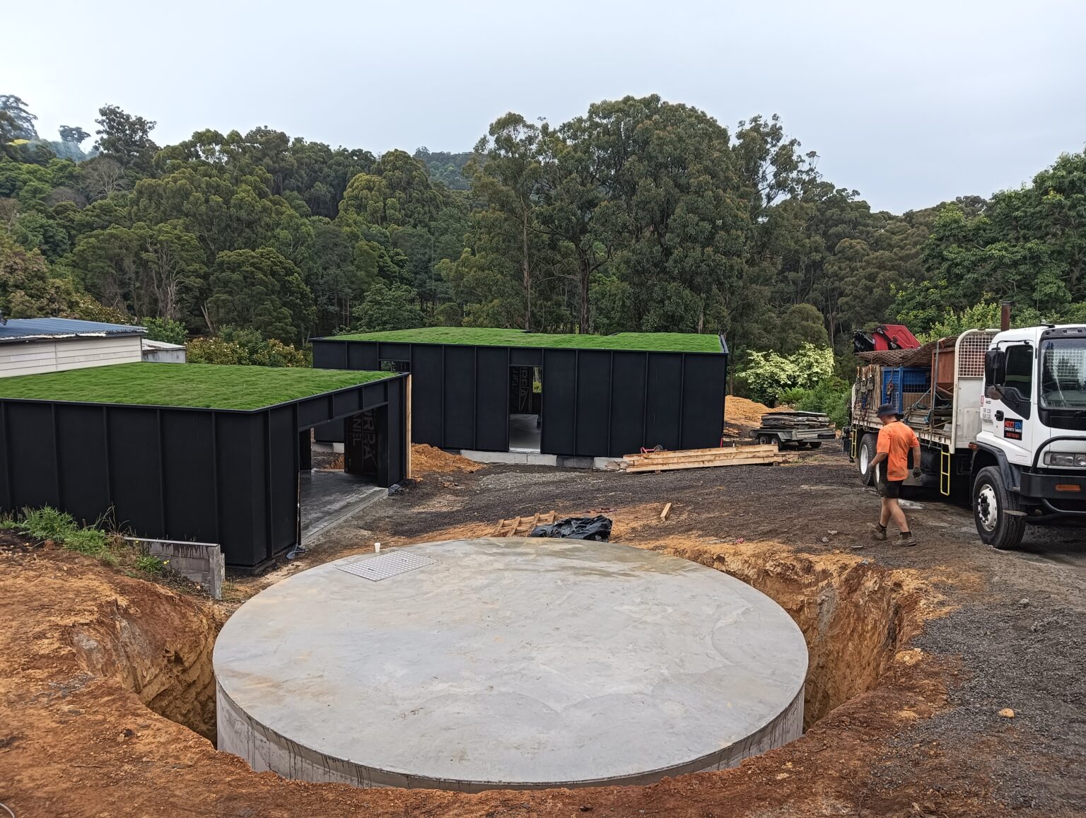 a 60000 litre concrete water tank in front of a house with grass on roof